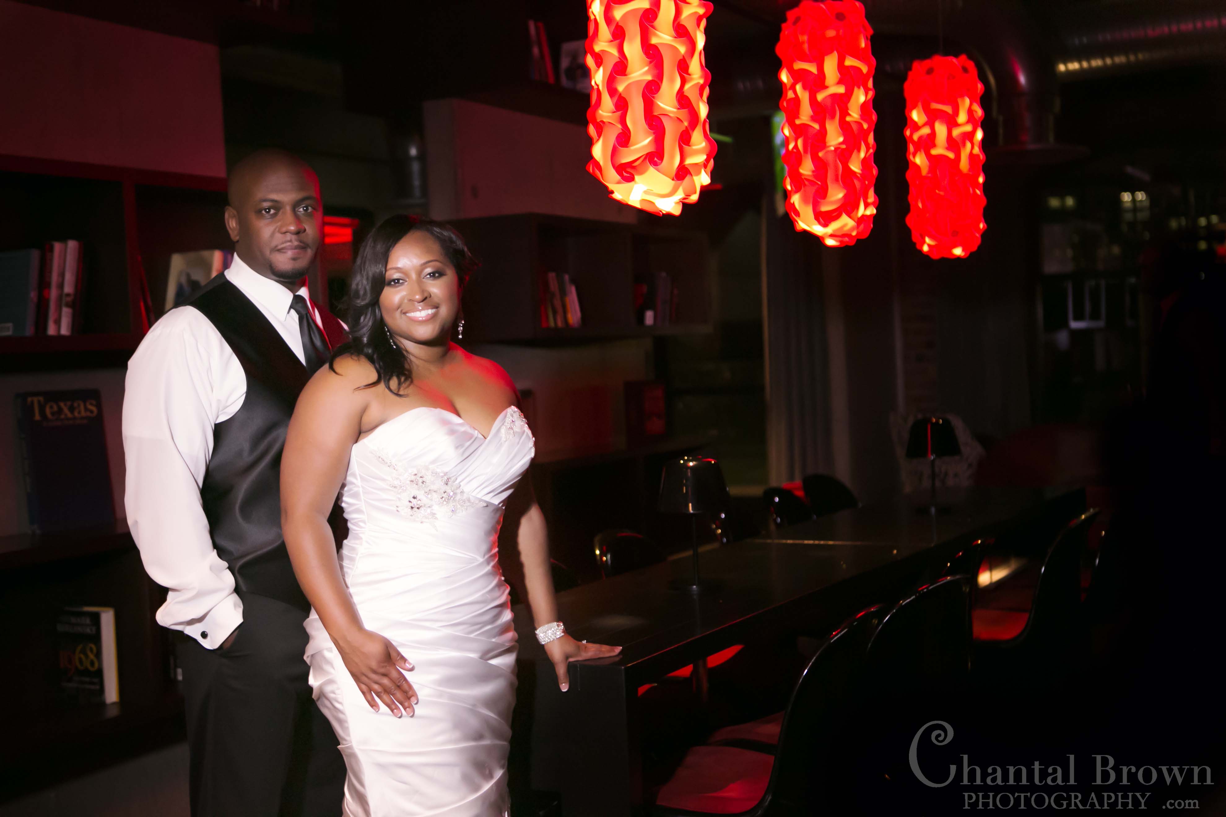 bride groom standing in NYLO hotel wedding reception by red colorful lights in Dallas Wedding Photographer